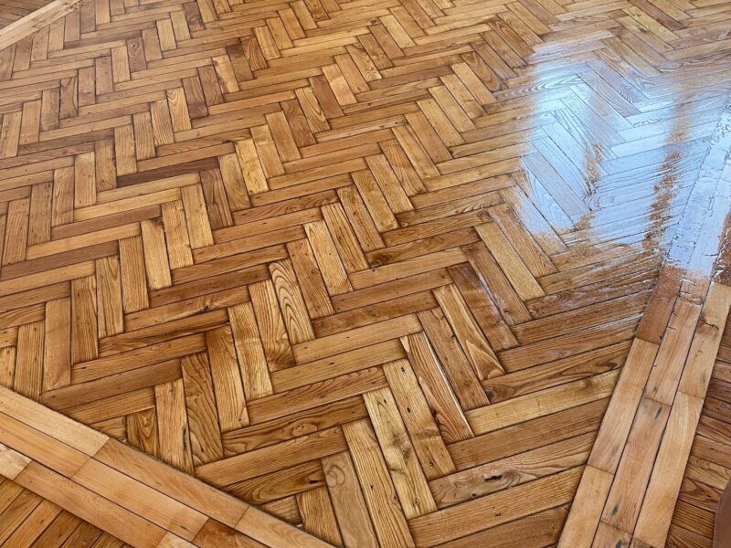 Pavimento in parquet a spina di pesce con superficie lucida e bordatura in legno